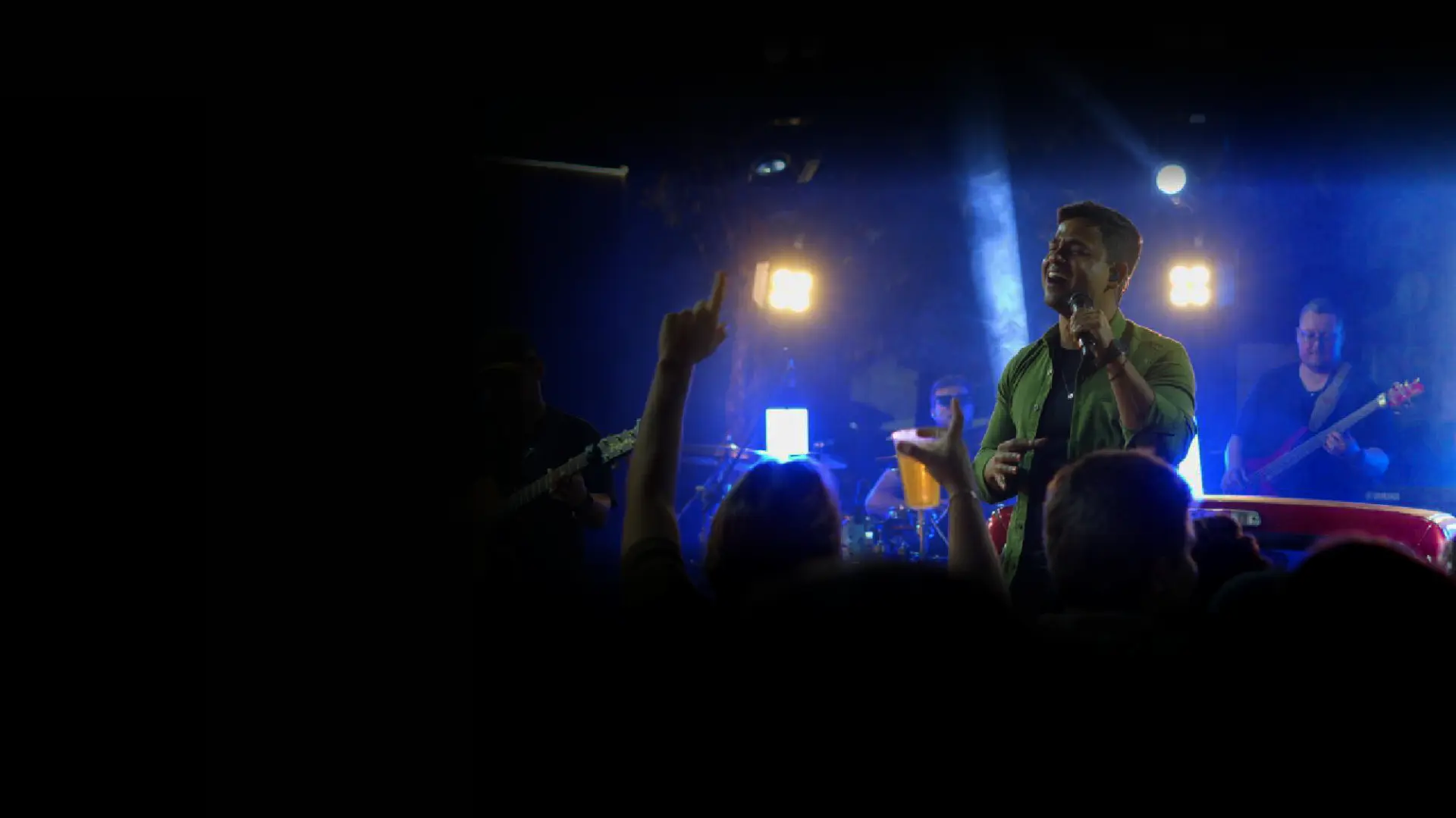 Luiz Fernando cantando no meio do público com a banda ao fundo